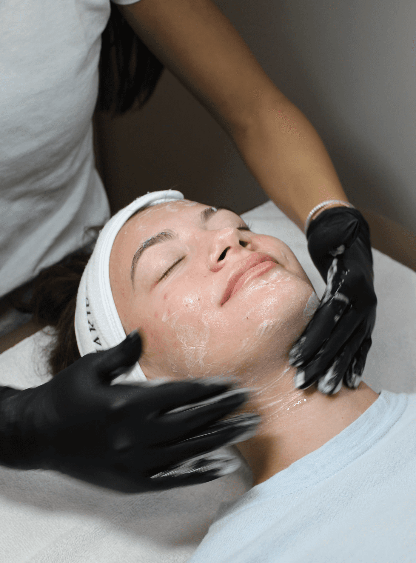 A Nakie Face aesthetician massaging cleanser into a client's skin during a facial